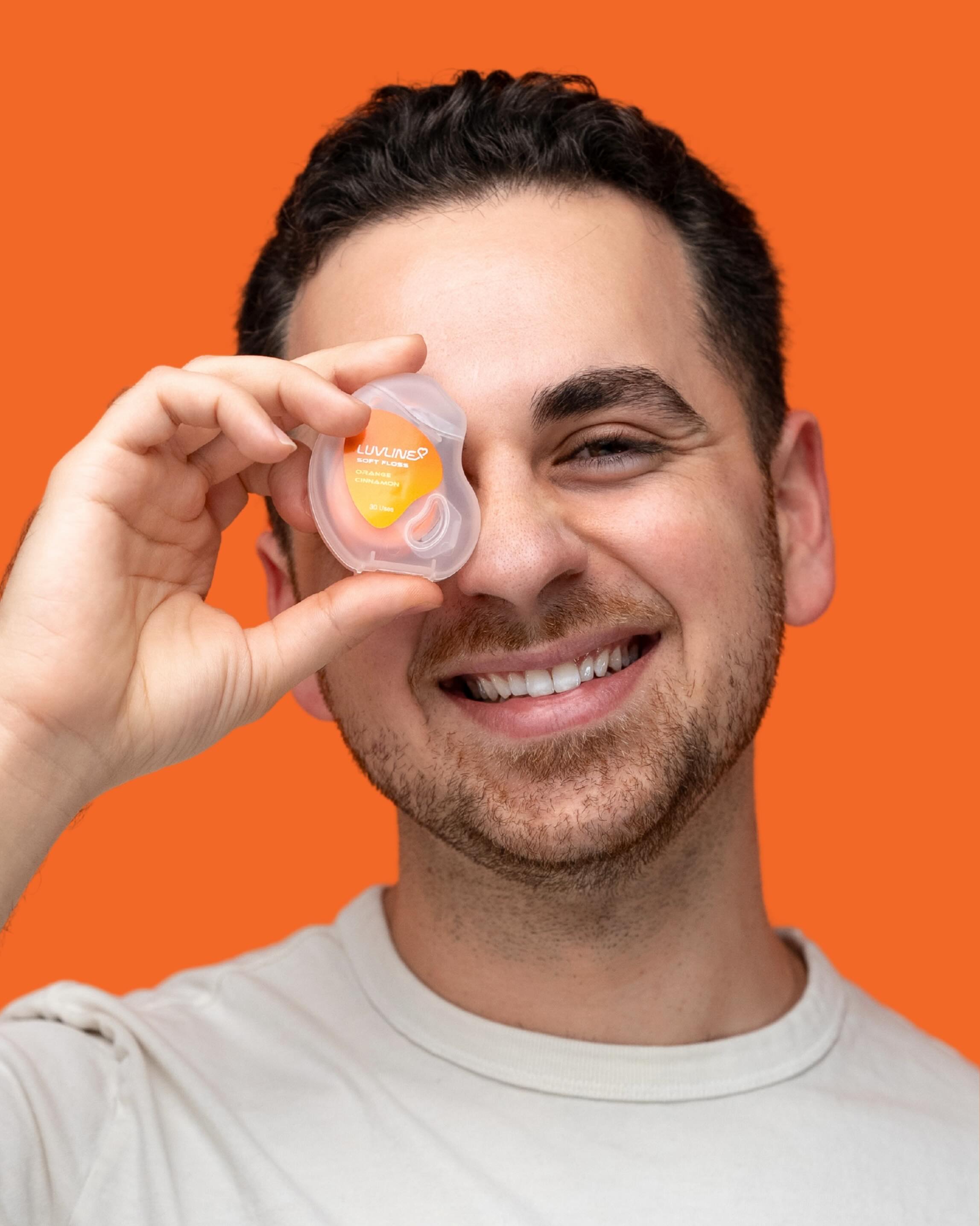 A LuvLine customer holding the floss dispenser playfully to his eye